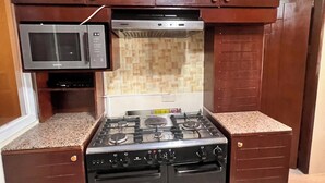 A kitchen with a built-in microwave, stove, and oven, under wooden cabinets with a tiled backsplash.