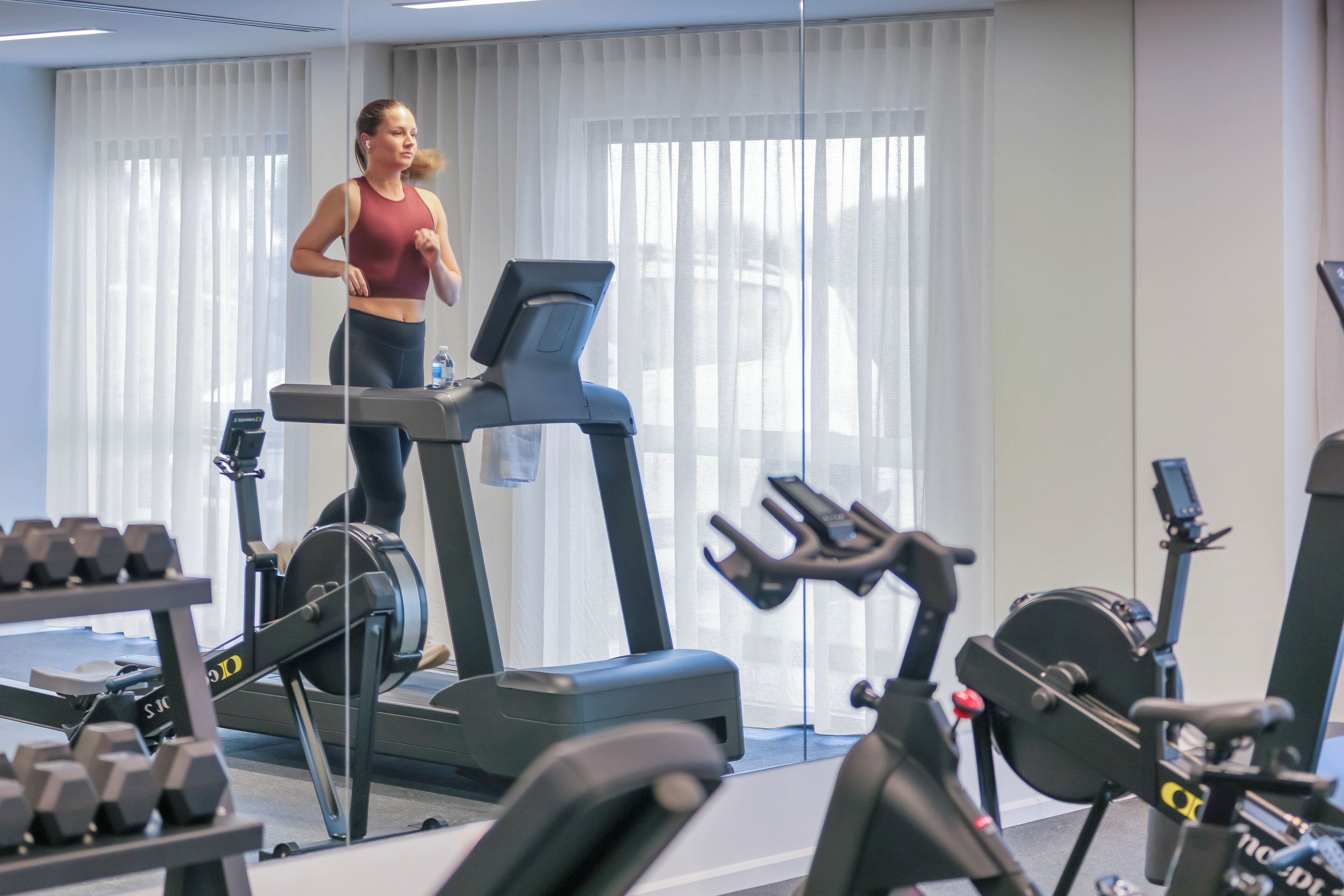 A gym with treadmills, dumbbells, and exercise equipment.