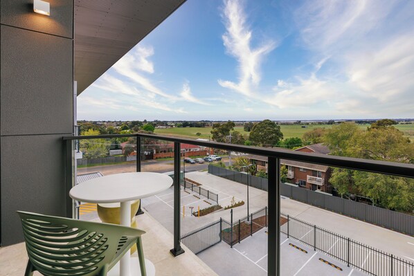 A balcony with a view of a parking lot and surrounding landscape.