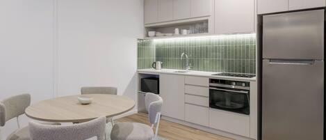 Una cocina moderna con una mesa redonda de comedor, sillas, un refrigerador, horno y microondas.