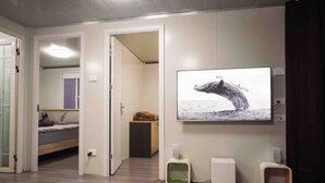 A modern room with a bed, a TV displaying a whale, and a cat tree.
