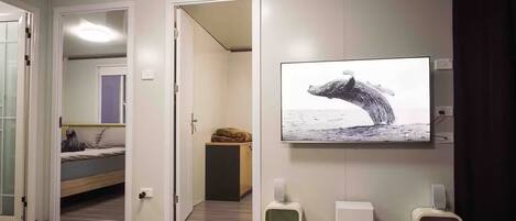 A modern room with a bed, a TV displaying a whale, and a cat tree.