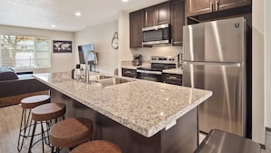 A modern kitchen with dark wood cabinets, stainless steel appliances, and a granite countertop. - Your stay will include the entire Unit A to yourself (Spokane)