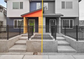 Un immeuble résidentiel moderne à deux étages, avec une façade grise et bleue, une porte verte et un toit rouge.