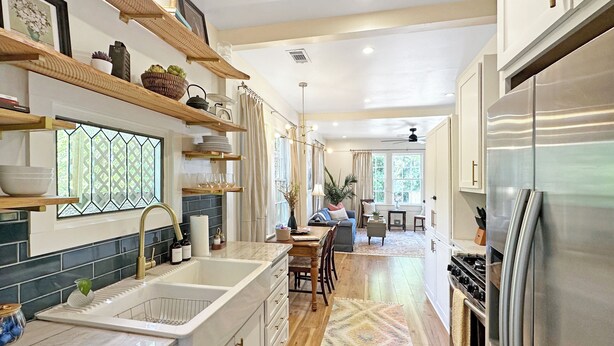 A modern kitchen with a stainless steel refrigerator, wooden shelves, and a large window. - Riverwalk Mill Cottage - Southern Charm Stay (Columbus)