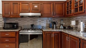 Una cocina con armarios de madera, microondas, estufa y salpicadero de azulejos.