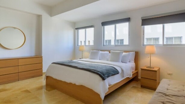 Un dormitorio con una cama, mesitas de noche, un aparador y una ventana.