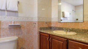 Un baño con inodoro, lavamanos y tocador con armarios.