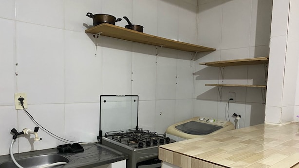 Eine Küche mit Gasherd, Spüle und Holzregalen darüber.