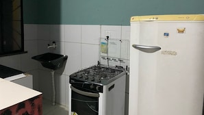 Eine kleine Küche mit Gaskochfeld, einem weißen Kühlschrank und einem Spülbecken.