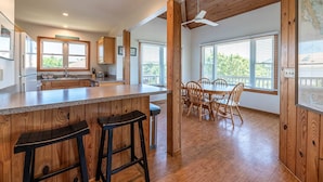 A modern kitchen with wooden accents, a bar area with stools, and large windows offering views of the outdoors.