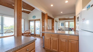A kitchen with wooden cabinets, a granite countertop, and a view of the outdoors.
