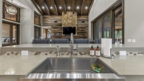 A modern kitchen with a large island, stainless steel appliances, and a stone accent wall.
