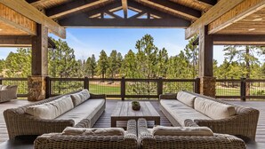 A covered outdoor seating area with wicker furniture and a stone pillar.