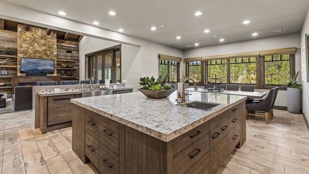 A modern kitchen with a large island, built-in appliances, and a stone accent wall.