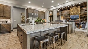 A modern kitchen with a large island, wooden cabinets, and a stone accent wall.