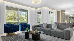 A modern living room with a grey sectional sofa, two blue armchairs, a round coffee table, and a patterned rug. - Magic & Adventure in This Stunning home in CG (Davenport)