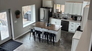 A modern kitchen with a central island, white cabinets, and a stainless steel refrigerator. - Sunrise Chalet on Potato Lake - Water Front - Dock - Game Room - Hot Tub (Rusk Township)