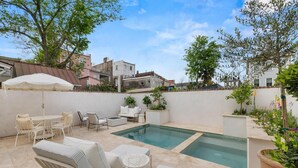Patio con piscina, muebles de exterior y plantas en macetas.