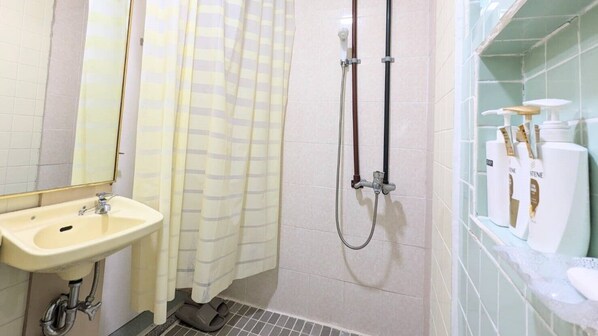 A bathroom with a sink, shower, and toiletries. - Avenue Koza Hotel (Okinawa)