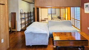 Una camera tradizionale in stile giapponese con due futon su tatami, un tavolo in legno e un'anta scorrevole che dà su un balcone.