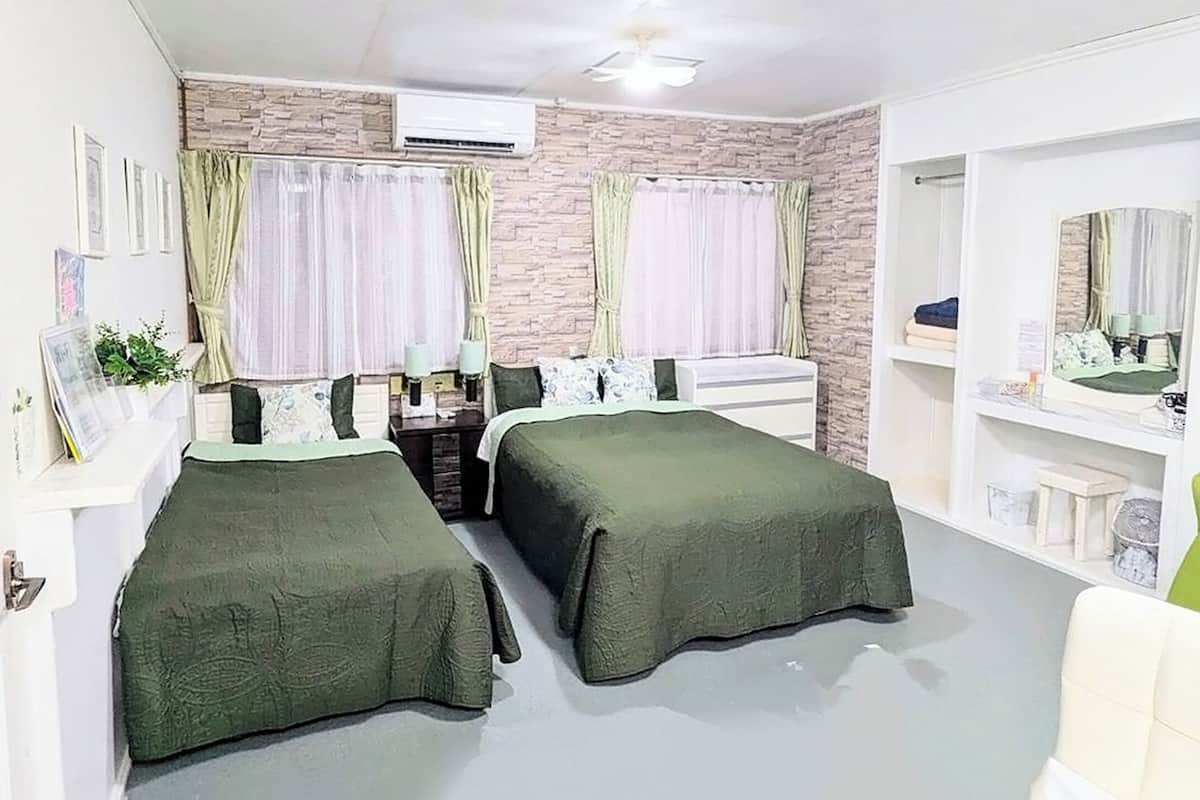Quarto com duas camas, sinal de banheiro, espelho e uma mesinha.