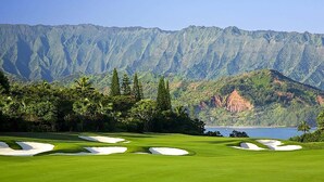 Ein Golfplatz mit Sandbunkern und einer Bergkulisse im Hintergrund.
