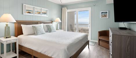 A bedroom with a bed, nightstands, a chair, a TV, and a balcony with a view.
