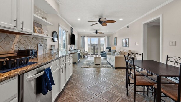 A spacious kitchen with granite countertops, a dishwasher, and a dining area with a table and chairs.