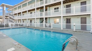 A swimming pool with a metal ladder, surrounded by a white fence.