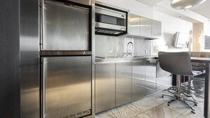 A modern kitchen with stainless steel appliances, a built-in oven, and a dining area with a chair and table. - SVS: Sunset View Studio | Open Balcony | Pool & Gym | Palms Place (Las Vegas)