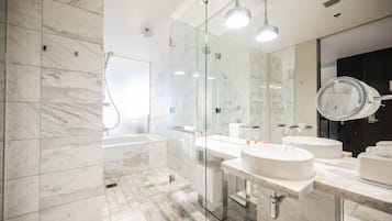 A modern bathroom with marble flooring, a glass-enclosed shower, and two sinks with mirrors.
