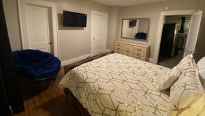 Ein Schlafzimmer mit Bett, Stuhl, Kommode und Spiegel.