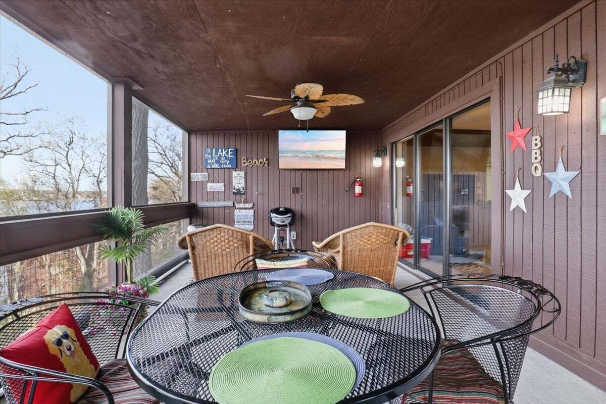 A covered outdoor seating area with a table, chairs, and a ceiling fan.