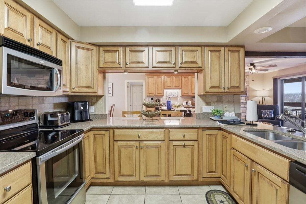 A kitchen with wooden cabinets, a microwave, stove, and a sink.