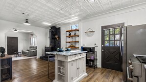 A spacious kitchen with a central island, wooden flooring, and a black door. - Charming 2-bedroom bungalow near downtown Atlanta (Atlanta)