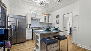 A modern kitchen with a stainless steel refrigerator, white cabinets, and a central island with bar stools. - Charming 2-bedroom bungalow near downtown Atlanta (Atlanta)