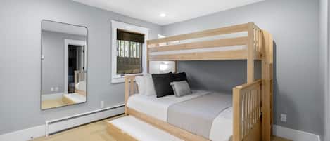 A bedroom with a bunk bed, a large mirror, a window with blinds, and a carpeted floor.