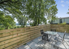 A patio with a wooden fence, a table, and chairs.