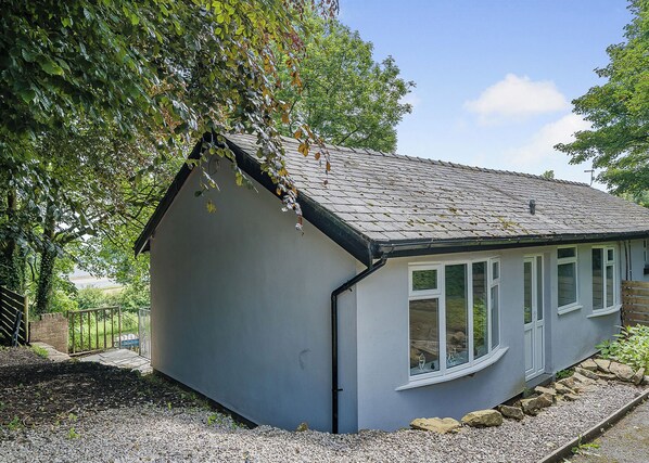 A small, single-story building with a sloped roof, white exterior walls, and multiple windows. - Beacon Fell Cottage 1 (Longridge, Ribble Valley)