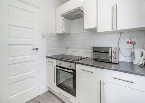 A kitchen with white cabinets, a built-in oven, a toaster, and a microwave. - Beacon Fell Cottage 1 (Longridge, Ribble Valley)