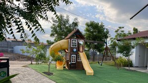 A playground with a yellow slide and a playhouse.
