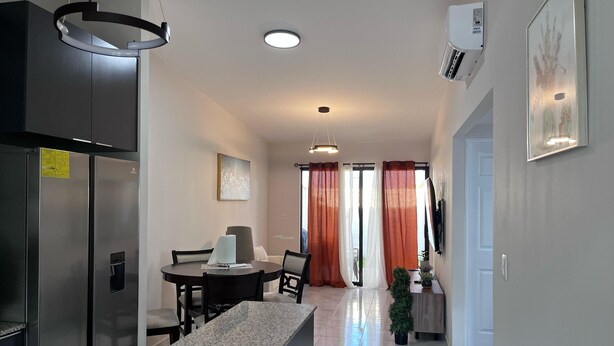 A modern kitchen with a granite countertop, stainless steel appliances, and a dining area with a table and chairs.