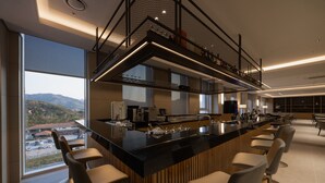 Una cucina moderna con un piano di lavoro nero, sgabelli da bar e vista sulle montagne.