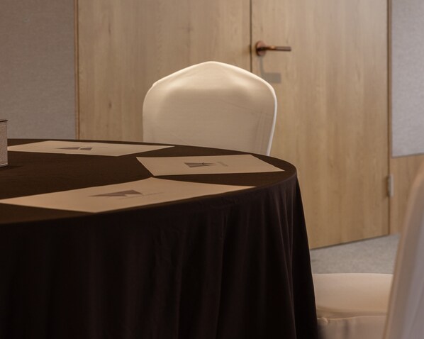 Una mesa redonda con mantel negro, papeles y una billetera.