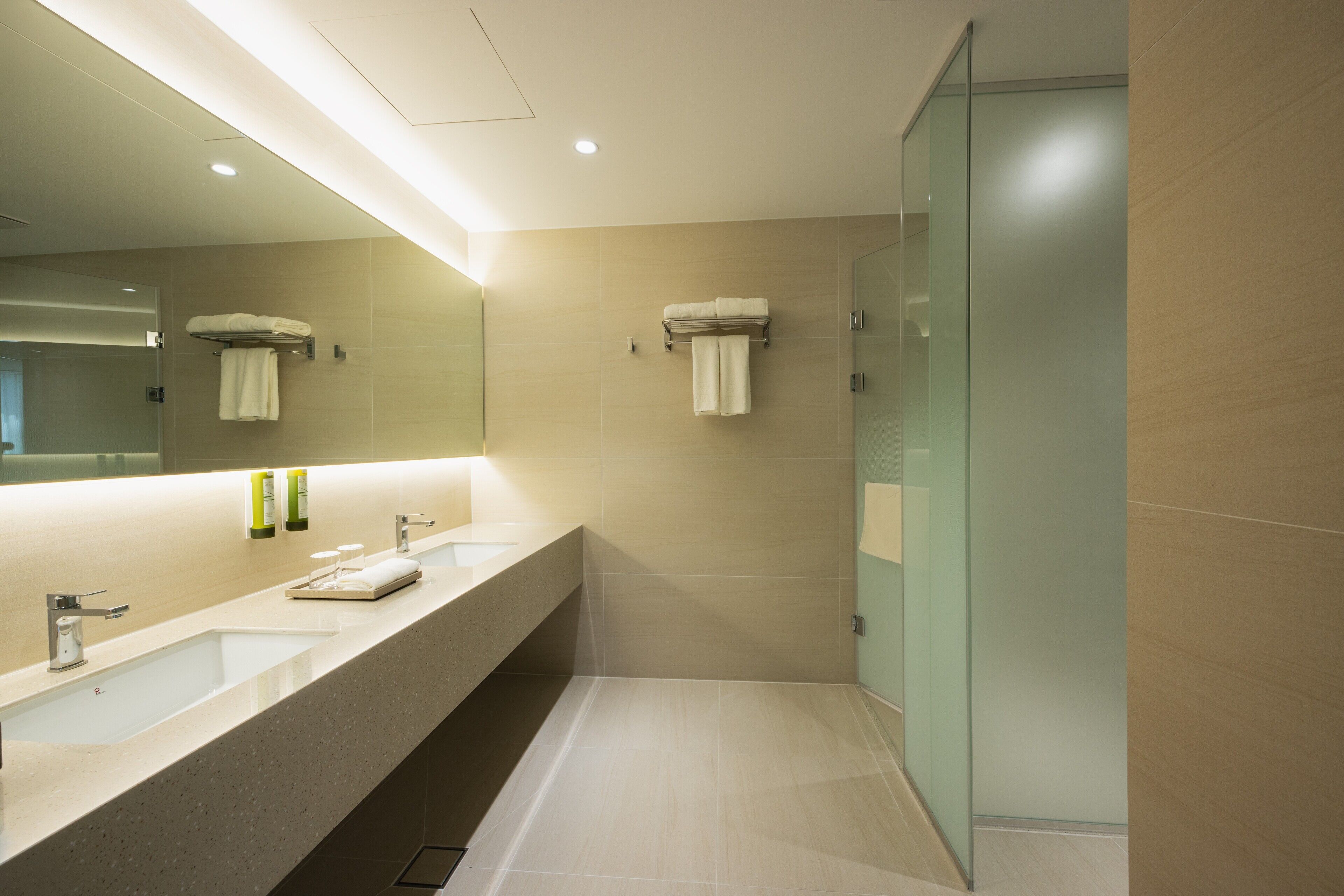 Un baño moderno con dos lavamanos, un espejo grande y una cabina de ducha de vidrio.
