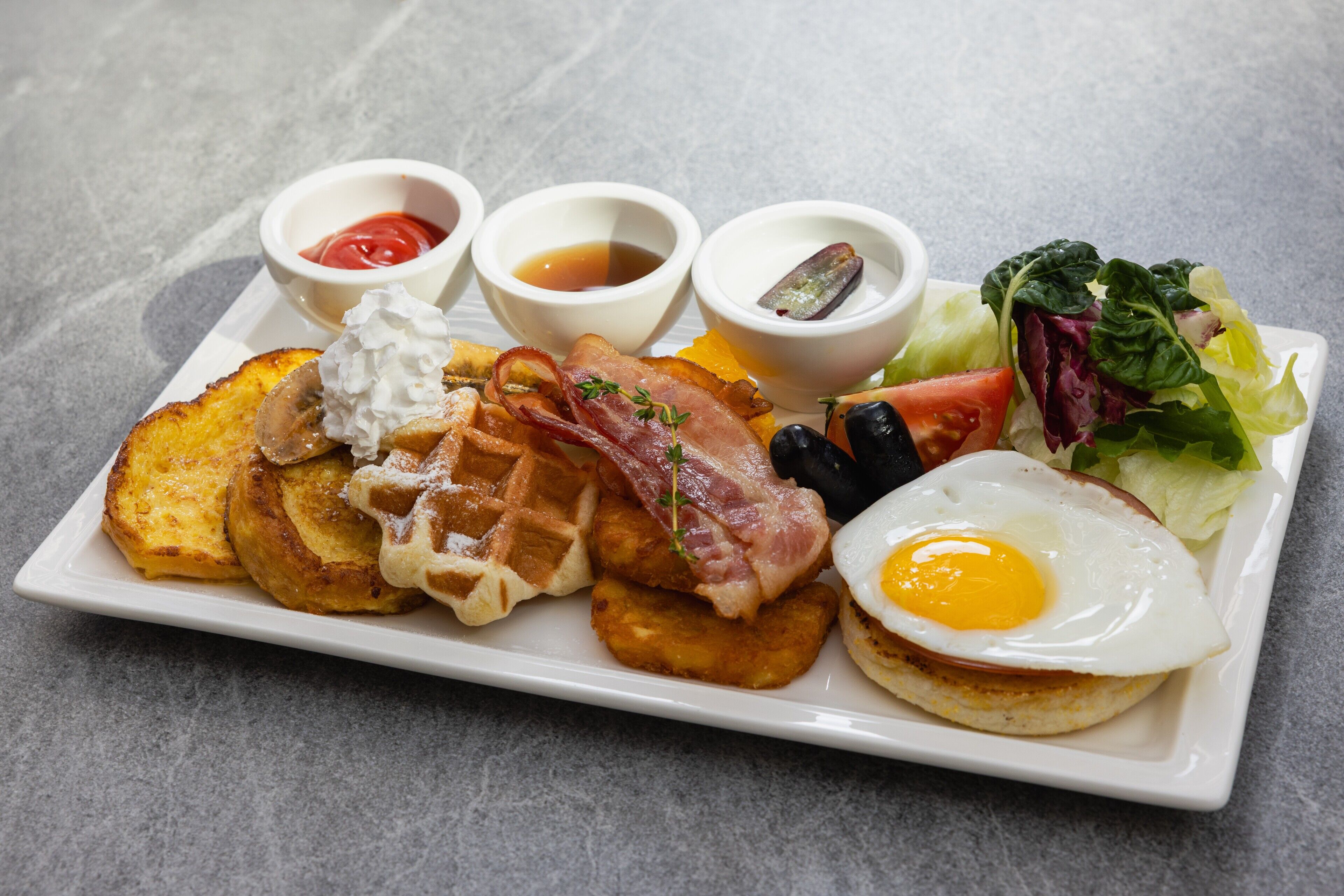 Une assiette de petit-déjeuner comprenant des toasts, du bacon, des œufs et des légumes.