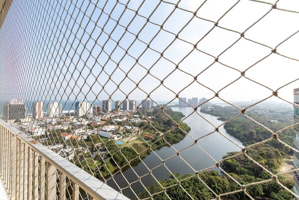 Un paisaje urbano con río, edificios y una cerca de malla metálica.