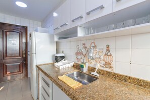 Een keuken met een granieten aanrecht, een roestvrijstalen spoelbak en witte kastjes.