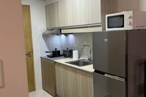 Cocina moderna con refrigerador de acero inoxidable, microondas y pileta.